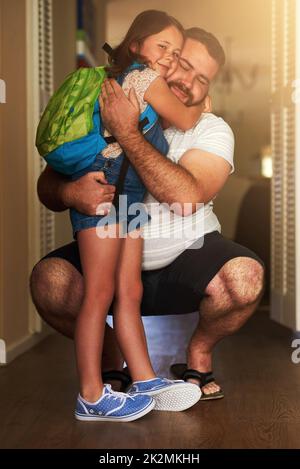 Das Beste am Schulbesuch ist, nach Hause zu kommen. Aufnahme eines entzückenden kleinen Mädchens, das ihren Vater umarmt, nachdem es von der Schule nach Hause gekommen war. Stockfoto