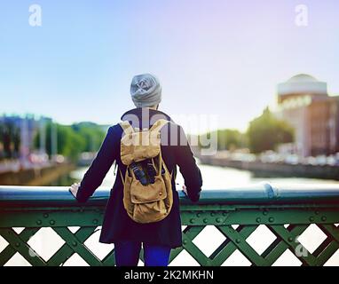 Die Stadt stellt alles in eine Perspektive. Rückansicht eines jungen Mannes, der von einer Brücke aus den Blick auf die Stadt schaute. Stockfoto