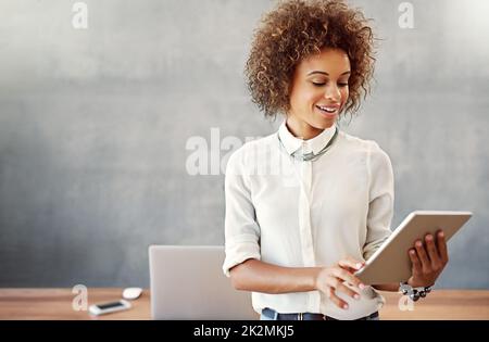 Sie nutzt jedes Tool für den Erfolg. Aufnahme einer jungen Frau, die zu Hause mit einem digitalen Tablet arbeitet. Stockfoto