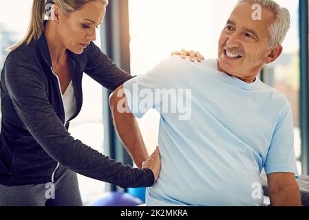 Druck ausüben, um die Schmerzen zu lindern. Aufnahme einer Physiotherapeutin, die eine ältere Patientin mit Rückenschmerzen in ihrem Büro untersucht. Stockfoto