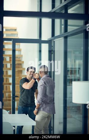 Brüder im Geschäft. Aufnahme von zwei jungen Geschäftsleuten, die in einem modernen Büro solidarisch die Hände greifen. Stockfoto