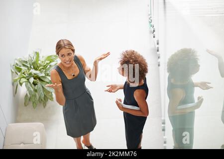 Frustriert am Arbeitsplatz. Eine Aufnahme einer verärgerten Geschäftsfrau im Gespräch mit einem Kollegen in einem modernen Büro. Stockfoto