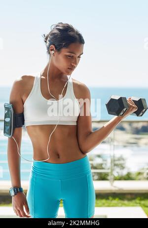 Der Weg zum Erfolg ist schweißtreibend. Kurzschuss einer jungen Frau, die in ihrem Workout Kurzhanteln verwendet. Stockfoto