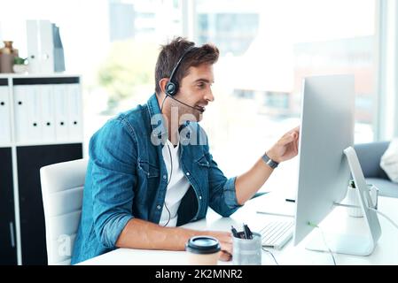 Ja, ich schaue mir jetzt alle Details an. Aufnahme eines attraktiven jungen Callcenter-Agenten, der in seinem Büro arbeitet. Stockfoto