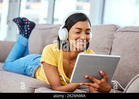 Ich höre mir meine Lieblingslieder an. Aufnahme eines Teenagers, das zu Hause Musik hört und ein Tablet benutzt. Stockfoto