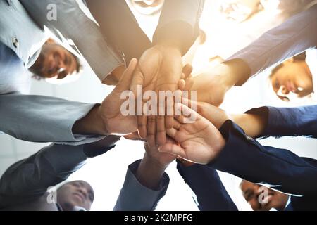 Teamarbeit an drei. Eine Aufnahme aus der unteren Perspektive einer Gruppe von Geschäftsleuten, die sich zusammenschließen. Stockfoto