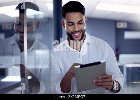 Ich liebe es, bei der Arbeit gute Nachrichten zu bekommen. Aufnahme eines jungen Geschäftsmannes, der sein digitales Tablet bei der Arbeit verwendet. Stockfoto