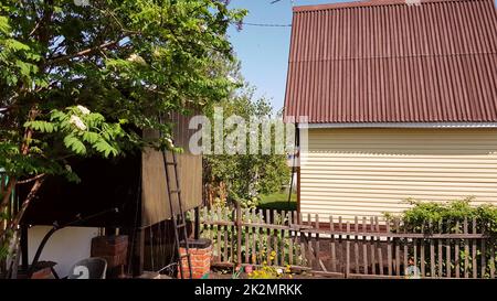 Modernes ländliches authentisches Haus mit Abstellgleis und Nebengebäuden im Hinterhof, das Konzept des Sommerlebens auf dem Land Stockfoto