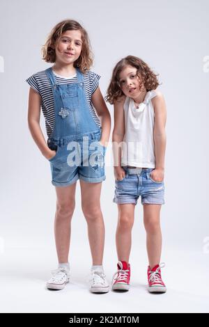 Zwei junge Schwestern stehen mit Händen in den Taschen Stockfoto