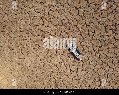 Verlassene Ruderboote auf gerissenen Böden auf dem Seenbett trockneten aufgrund der globalen Erwärmung und Dürre aus. Stockfoto