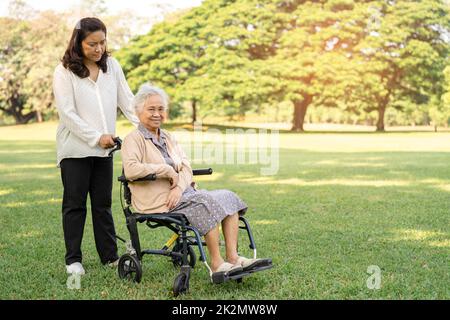 Pflegepersonal Hilfe und Pflege Asiatische ältere oder ältere alte Dame Frau Patientin sitzt im Rollstuhl im Park, gesund starke medizinische Konzept. Stockfoto