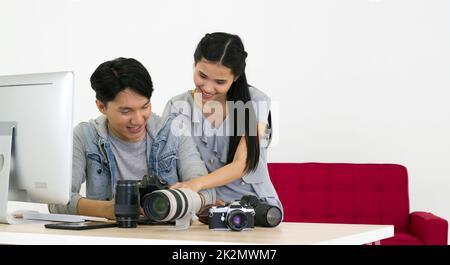 Asiatischer Fotograf und Modell, der sich Bilder ansieht, die auf dem Kamerabildschirm aufgenommen wurden. Das junge Model ist sehr zufrieden mit ihrem Foto. Die Atmosphäre im Fotostudio. Stockfoto