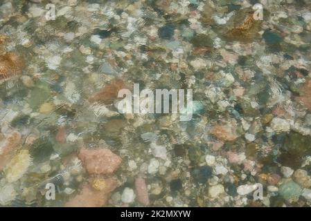 Ein Fragment eines Gebirgsflusses. Bunte Steine unter dem Wasser. Stockfoto