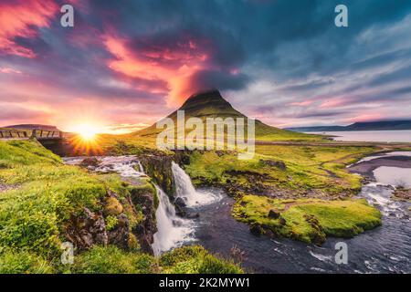 Fantastische Landschaft mit Sonnenuntergang über Kirkjufell Berg mit Kirkjufellsfoss Wasserfall und bunte Pileus Wolke im Sommer auf Island Stockfoto