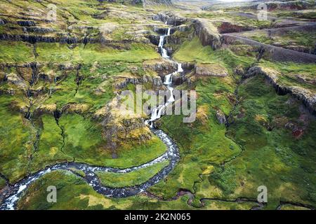 Luftaufnahme des wunderschönen Klifbrekkufossar Wasserfalls, der im Mjoifjordur Fjord im Sommer in Island fließt Stockfoto