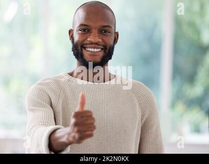 Ich stimme zu. Aufnahme eines jungen Mannes, der zu Hause einen Daumen nach oben zeigt. Stockfoto