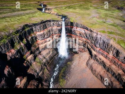 Luftaufnahme des Hengifoss-Wasserfalls, umgeben von Schichten basaltischer Schichten mit im Sommer fließendem Wasser im Osten Islands Stockfoto