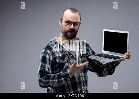 Zufriedener Mann, der auf sein tragbares Notebook zeigt Stockfoto