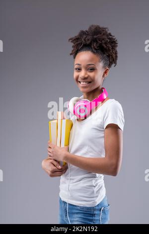 Glückliches, lebhaftes Teenager Mädchen mit bunten Lehrbüchern Stockfoto