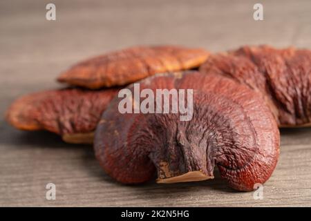 Getrockneter Lingzhi-Pilz auf hölzernem Hintergrund, gesundes Kräuterfutter. Stockfoto