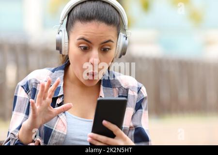 Erstaunte Teenager, die Musik hören und Inhalte auf dem Telefon finden Stockfoto