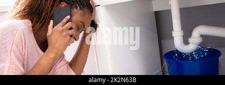 Eine Frau Ruft Den Klempner Vor Dem Undichten Waschbecken Stockfoto