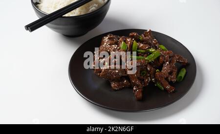 Mongolisches Fleisch in Sauce mit Reis. Traditionelle asiatische Gerichte unter Rühren braten Stockfoto