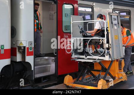 Neapel, Italien - 21. September 2022: Im Bahnhof wird ein behinderter Fahrgast im Rollstuhl mit einem speziellen für auf dem Zugwagen transportiert Stockfoto