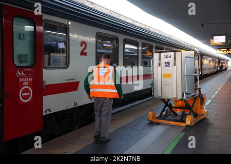Neapel, Italien - 21. September 2022: Im Bahnhof manövrieren zwei Fahrer den speziellen Gabelstapler, der für den Transport von Behinderten im Zug verwendet wird Stockfoto