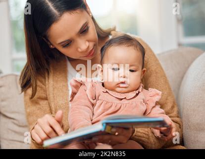 Sie liebt ein gutes Bilderbuch. Aufnahme einer Frau, die ihr kleines Mädchen vorliest. Stockfoto