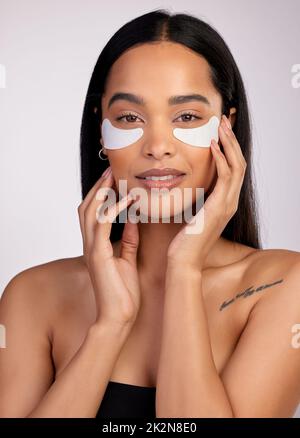 Denn wer will Taschen. Studioporträt einer attraktiven jungen Frau, die unter Augenflecken vor einem rosa Hintergrund trägt. Stockfoto