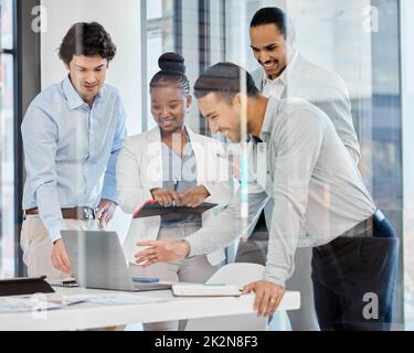Ein technologieorientiertes Team. Aufnahme einer Gruppe von Geschäftsleuten, die in einem modernen Büro Brainstorming und Ideenaustausch durchführen. Stockfoto