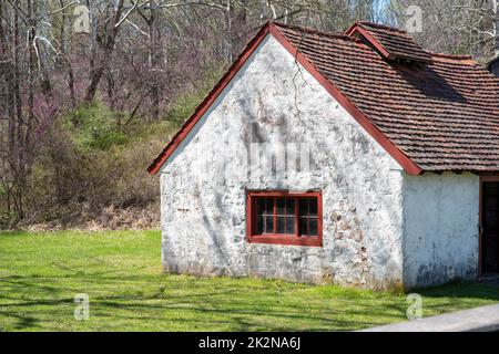 Seitenblick auf ein weißes Steinhaus mit antiken roten Fenstern in ländlicher Landschaft Stockfoto