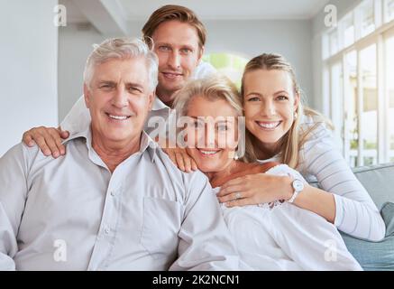 Porträt einer glücklichen Familie über das Wochenende auf der Couch zusammen. Eltern besuchen ihren erwachsenen Sohn und ihre Tochter mit einem Lächeln, Liebe und Unterstützung Stockfoto