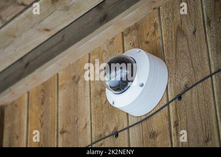 Rund geformte wetterdichte Sicherheitskamera an der Holzwand Stockfoto