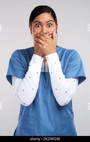 Eine himmlische Sphäre, waren schwerelos wie die Wellen, die verschwinden. Porträt eines schockierten jungen Arztes in Scrubs vor weißem Hintergrund. Stockfoto