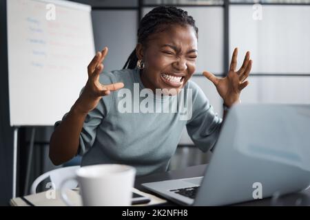 Wie kann es wagen, dass dieses Ding auf mich abstürzt. Aufnahme einer jungen Geschäftsfrau, die wütend aussieht, während sie einen Laptop im Büro benutzt. Stockfoto