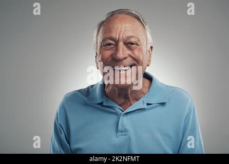 Ich fühle mich heute wie im auf Cloud 9. Aufnahme eines Mannes, der vor grauem Hintergrund fröhlich die Kamera in einem Studio anlächelt. Stockfoto