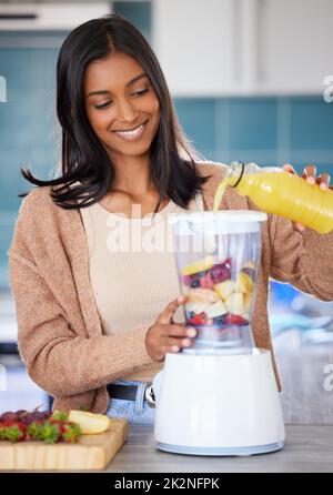 Ein köstliches Getränk in nur wenigen Minuten aufschlagen. Aufnahme einer jungen Frau, die zu Hause einen gesunden Smoothie vorbereitet. Stockfoto