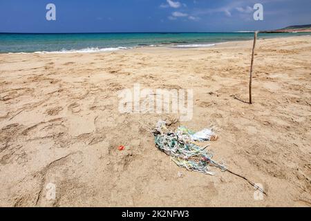 Perfekter leerer, unberührter Strand, kleiner Müllhaufen (verwickelte Plastikseile) auf feinem Sand, ruhiges Meer im Hintergrund. Ozeanabfallkonzept. Karpass, Nordzypern Stockfoto
