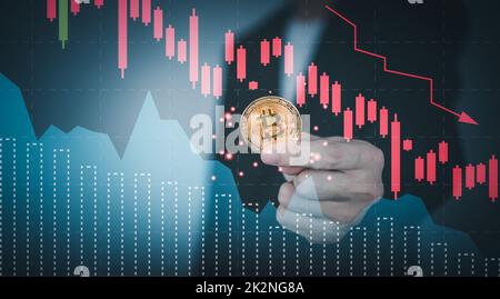 Bitcoin-Preisabsturz fällt mit Grafik nach unten. Mann Hand hält Kryptowährung. Konzept des Bärenmarktes. Stockfoto