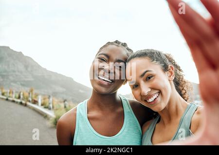 Dokumentieren unserer Fitness-Reise. Aufnahme von zwei jungen Frauen, die während des Trainings in der Natur ein Selfie machen. Stockfoto