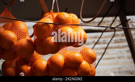 Haufen Orangen in roten Saitenbeuteln zum Verkauf auf dem lokalen Markt an einem Straßenstand in Nazareth, Israel Stockfoto