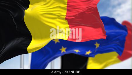 Detail der im Wind winkenden Nationalflagge Belgiens mit verschwommener eu-Flagge im Hintergrund an einem klaren Tag Stockfoto
