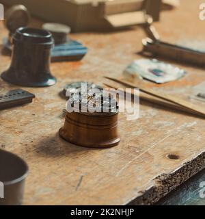 Der alte Uhrenmechanismus wurde zur Reparatur auf einer Werkbank demontiert Stockfoto