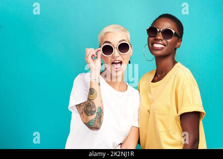 Die Zukunft sieht sicher hell aus. Studioaufnahme von zwei jungen Frauen, die eine Sonnenbrille auf türkisfarbenem Hintergrund tragen. Stockfoto