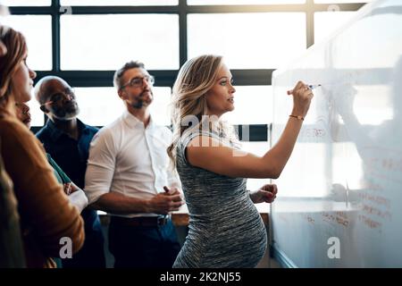 Verteilen ihrer Aufgaben. Aufnahme einer Schwangeren Geschäftsfrau, die im Sitzungssaal eine Präsentation gehalten hat. Stockfoto