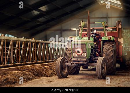 Old Faithful. Aufnahme eines rostigen alten Traktors, der in einer leeren Scheune steht. Stockfoto