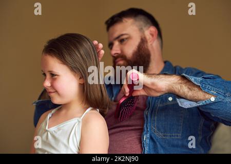 Inspirierende Momente. Aufnahme eines Vaters, der sich zu Hause die Haare seiner Tochter putzt. Stockfoto