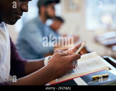 Er liebt es, dass er seine Antworten sofort überprüfen kann. Eine kurze Aufnahme von Studenten, die ihre Smartphones im Unterricht nutzen. Stockfoto